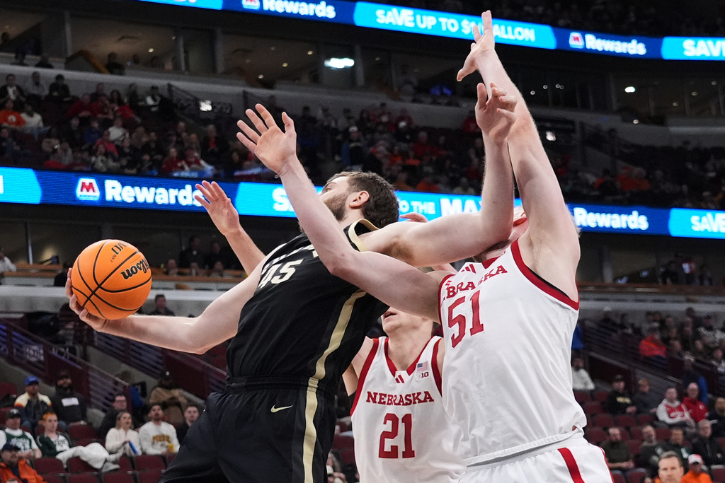 Purdue center Oscar Cluff, left, rebounds the ball against Nebraska forwards Pryce Sandfort (21) and Rienk Mast (51) during the first half of an NCAA college basketball game in the quarterfinals of the Big 10 Conference tournament, Friday, March 13, 2026, in Chicago. (AP Photo/Nam Y. Huh)