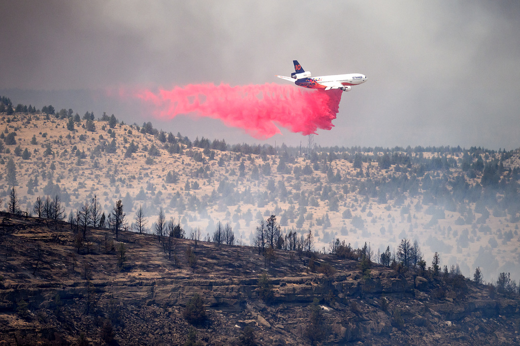 An air tanker drops retardant while battling the Bench fire on Saturday, July 25, 2026, in Jefferson County, Ore. (AP Photo/Noah Berger)