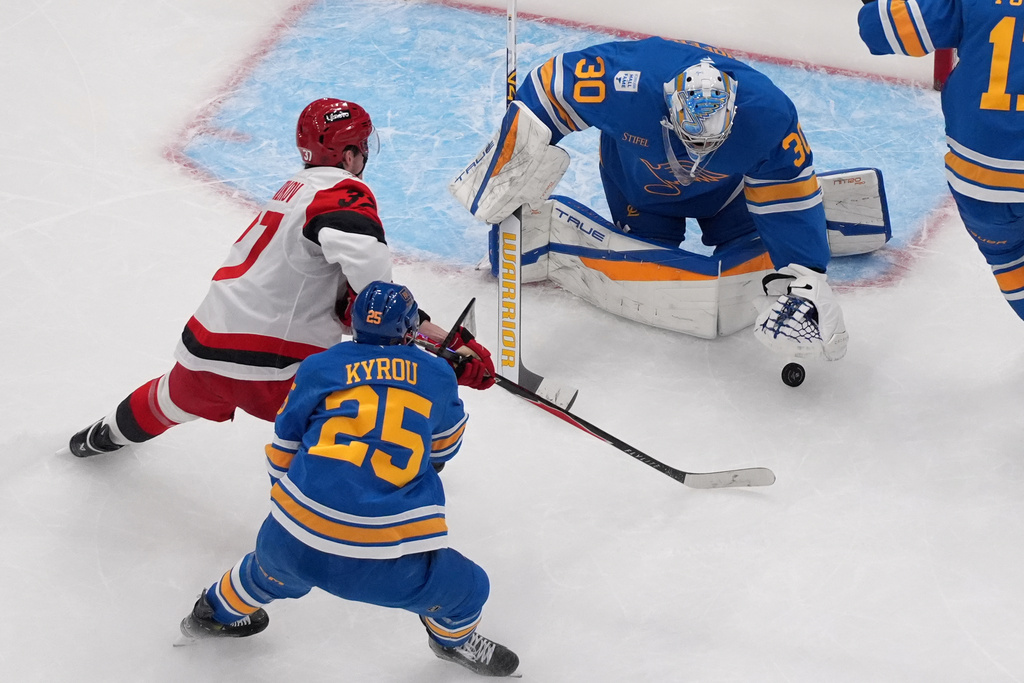 St. Louis Blues goaltender Joel Hofer (30) grabs a loose puck as teammate Jordan Kyrou (25) and Carolina Hurricanes' Andrei Svechnikov (37) watch during the second period of an NHL hockey game Tuesday, Jan. 13, 2026, in St. Louis. (AP Photo/Jeff Roberson)