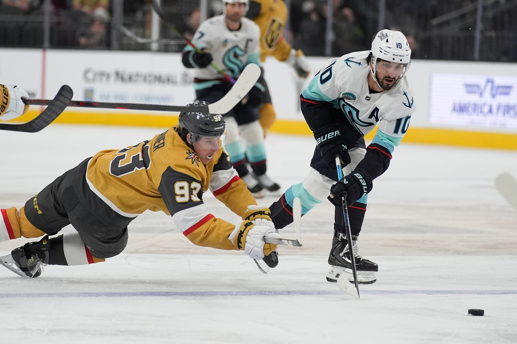 Vegas Golden Knights right wing Mitch Marner (93) and Seattle Kraken center Matty Beniers (10) battle for the puck during the second period of an NHL hockey game Wednesday, April 15, 2026, in Las Vegas. (AP Photo/John Locher)