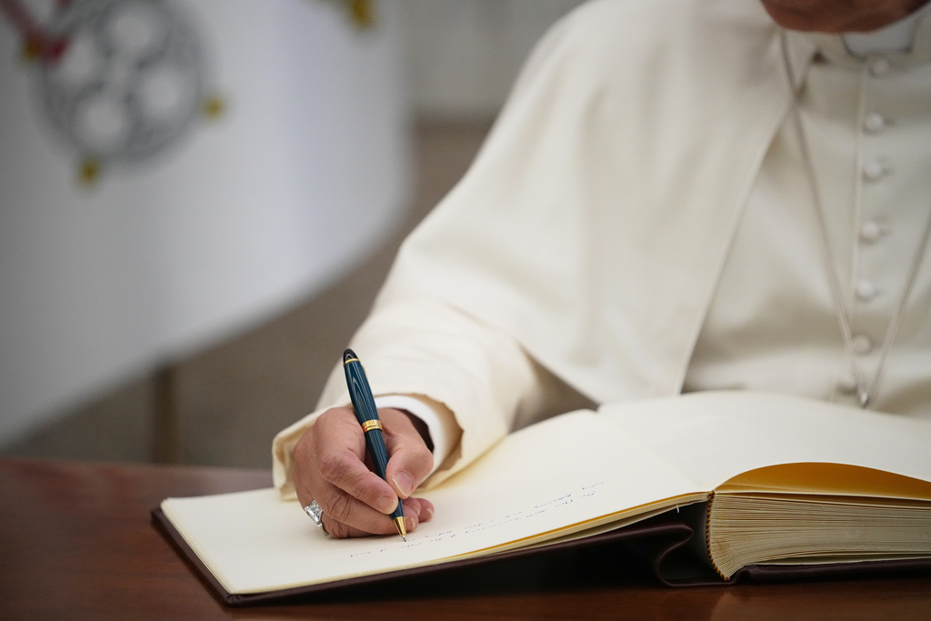 Pope Leo XIV signs the FAO Golden Book register of honor as he attends a ceremony marking the 80th anniversary of World Food Day at the FAO headquarters in Rome, Thursday, Oct. 16, 2025. (AP Photo/Alessandra Tarantino)
