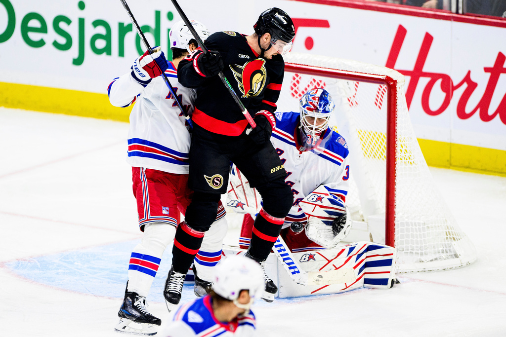 New York Rangers goaltender Igor Shesterkin (31) tracks the puck through teammate Braden Schneider (left) and Ottawa Senators' Drake Batherson (19) during third period NHL hockey action in Ottawa, on Thursday, Dec. 4, 2025.(Spencer Colby/The Canadian Press via AP)