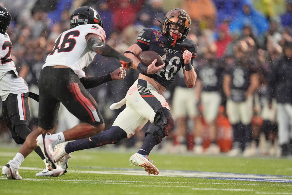 Navy fullback Alex Tecza (46) runs the ball for a first down past Cincinnati safety Antwan Peek Jr., left, uring the first half of the Liberty Bowl NCAA college football game Friday, Jan. 2, 2026, in Memphis, Tenn. (AP Photo/George Walker IV)