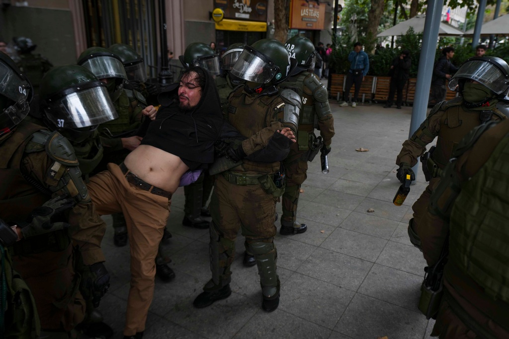 Riot police detain a protester during a march during World Water Day demanding greater environmental protection and animal welfare, in Santiago, Chile, Sunday, March 22, 2026. (AP Photo/Esteban Felix)