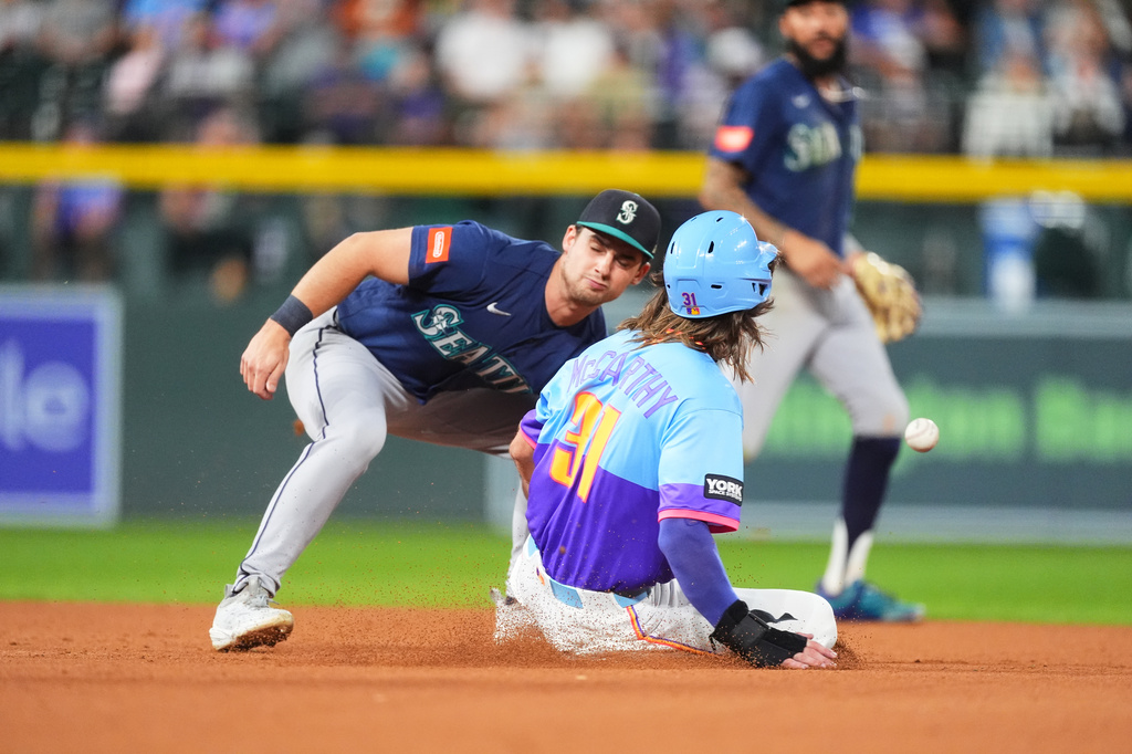 Seattle Mariners second baseman Cole Young, left, misses a pickoff throw as Colorado Rockies' Jake McCarthy, right, steals second in the fourth inning of a baseball game Friday, Sept. 18, 2026, in Denver. (AP Photo/David Zalubowski)