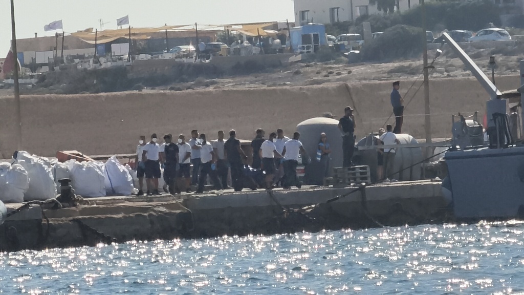 Italian Coast Guards officers carry a body bag on the dock of Lampedusa harbor Wednesday, Aug. 13, 2025, after a boat carrying nearly 100 migrants capsized off the Italian island, killing several people and leaving another dozen missing. (AP Photo/Elio Deisderio)