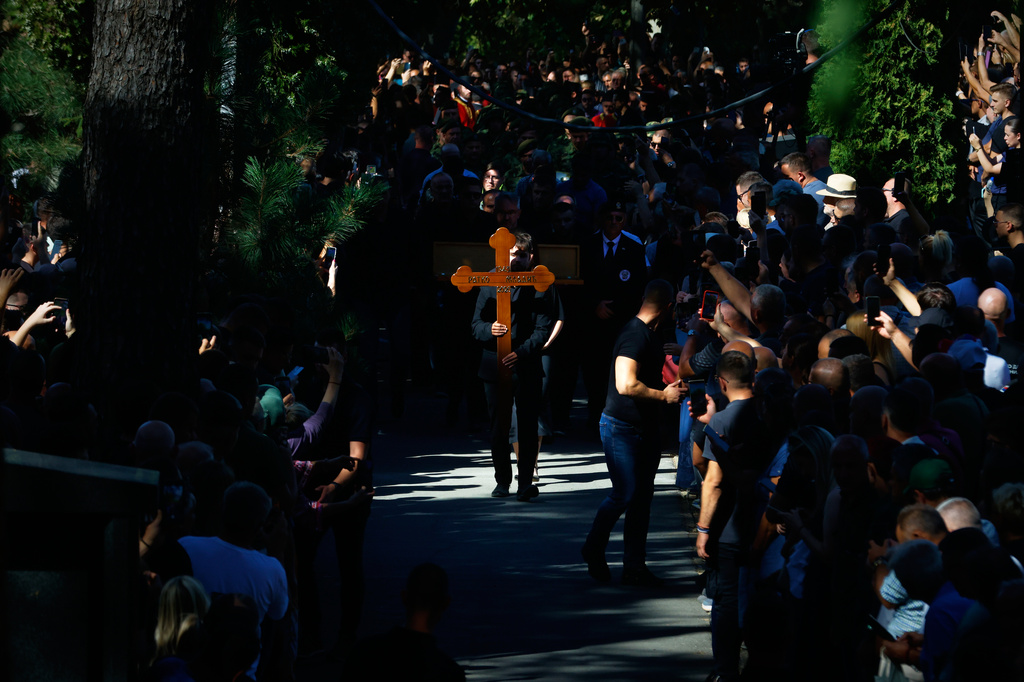 A young man carries the cross of the former Bosnian Serb army commander Ratko Mladic, who died last week while serving a life sentence for genocide and other atrocities during the war in Bosnia, at the Topcider Cemetery, in Belgrade, Serbia, Monday, Sept. 7, 2026. (AP Photo/Marko Drobnjakovic)