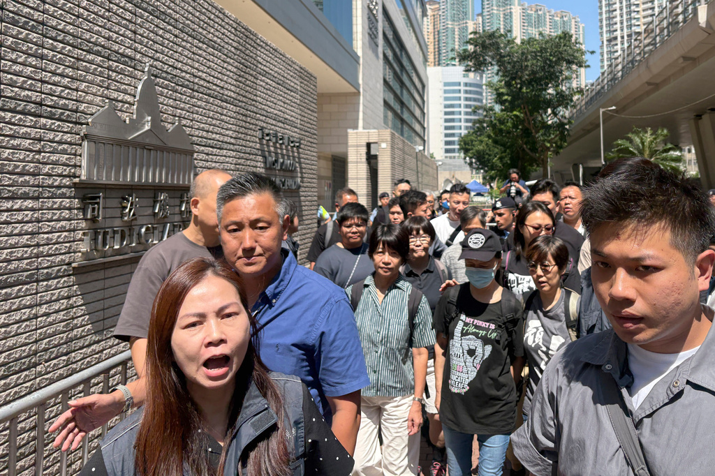 Medina Chow Lau Wah-chun, third from right in black, mother of Chow Hang-tung, and Elizabeth Tang, fourth from right in green stripes, wife of Lee Cheuk-yan, is flanked by supporters as they leave the court in Hong Kong, Friday, Sept. 11, 2026, after the sentencing for the Hong Kong activists who organized annual Tiananmen vigils. (AP Photo/Kanis Leung)