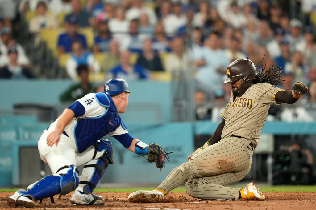 San Diego Padres' Fernando Tatis Jr., right, scores on a sacrifice fly by Manny Machado as Los Angeles Dodgers catcher Will Smith makes a late tag during the fifth inning of a baseball game Wednesday, Sept. 23, 2026, in Los Angeles. (AP Photo/Mark J. Terrill)