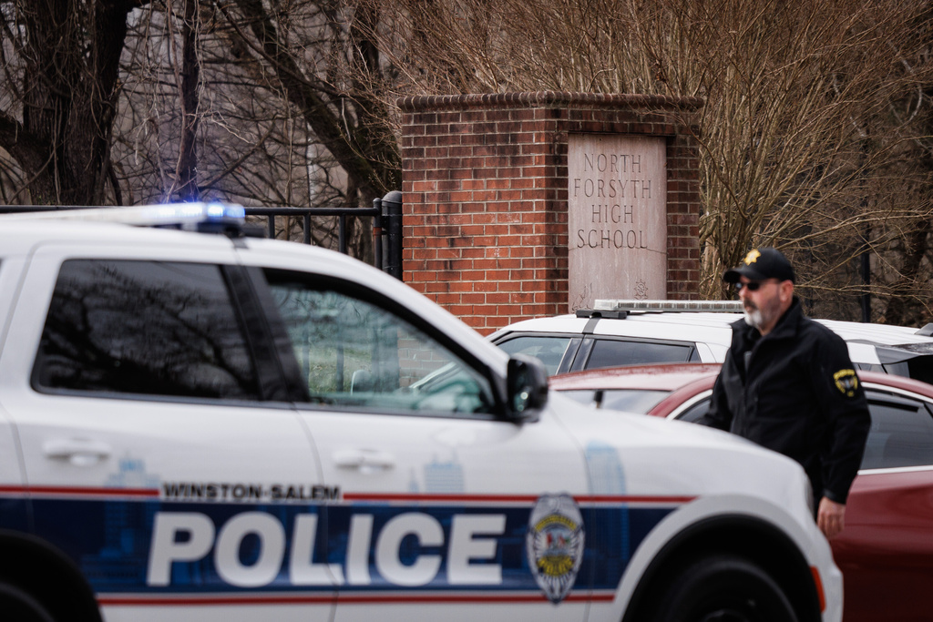 Winston-Salem police officers and Forsyth County sheriff's deputies block the gate leading to North Forsyth High School after a fatal stabbing, Tuesday, Dec. 9, 2025, in Winston-Salem, N.C. (Allison Lee Isley/The Winston-Salem Journal via AP)