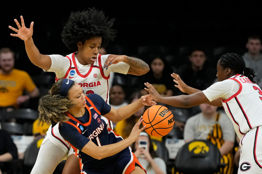 Virginia guard Paris Clark (1) passes between Georgia forward Mia Woolfolk, left, and guard Dani Carnegie, right, during the first half in the first round of the NCAA college basketball tournament, Saturday, March 21, 2026, in Iowa City, Iowa. (AP Photo/Charlie Neibergall)
