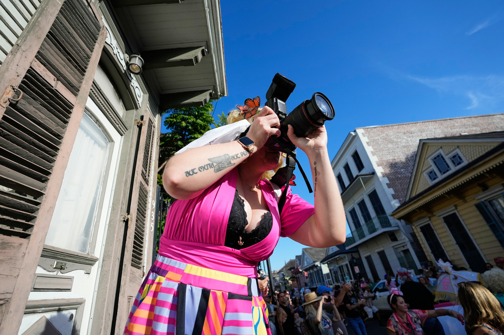 A person takes photos as members of the Krewe of Dolly lead a second line parade in commemoration of the life of Dolly Parton through the French Quarter Friday, Sept. 25, 2026, in New Orleans. (AP Photo/Gerald Herbert)