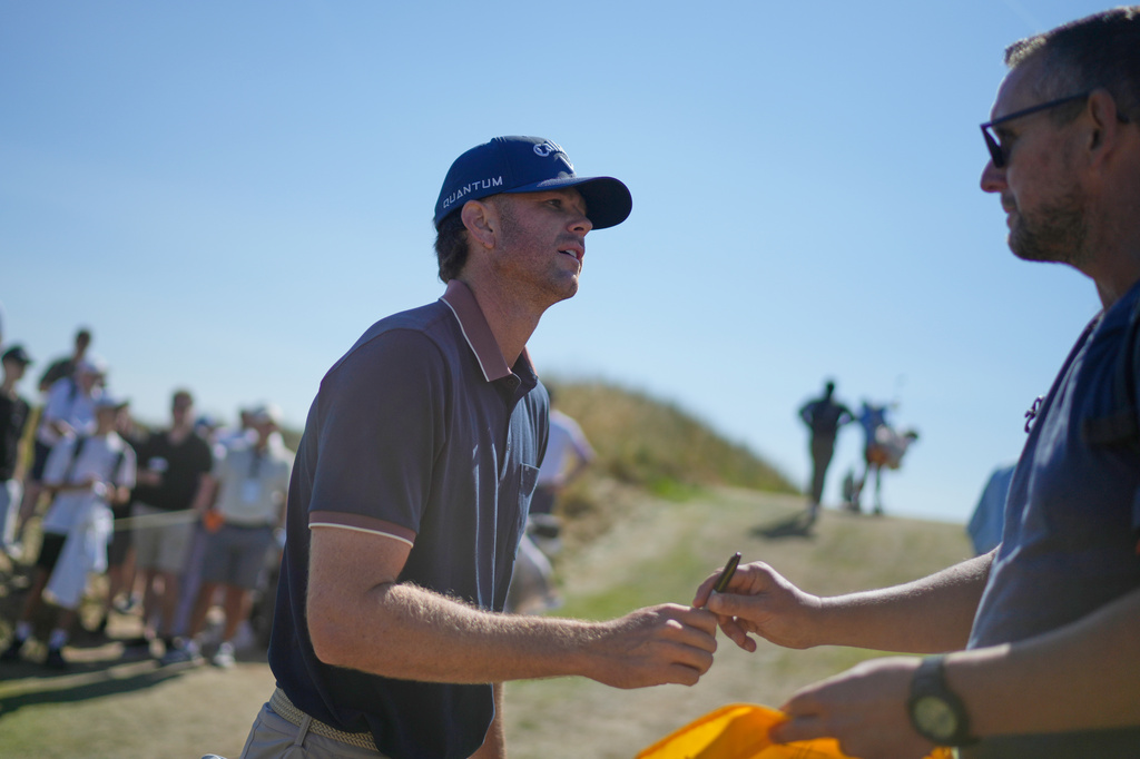 Marcus Plunkett of the United States signs an autograph for a fan between the 12th and 13th holes during a practice round for the British Open Golf championships at Royal Birkdale golf club, in Southport, England, Tuesday, July 14, 2026. (AP Photo/David Goldman)