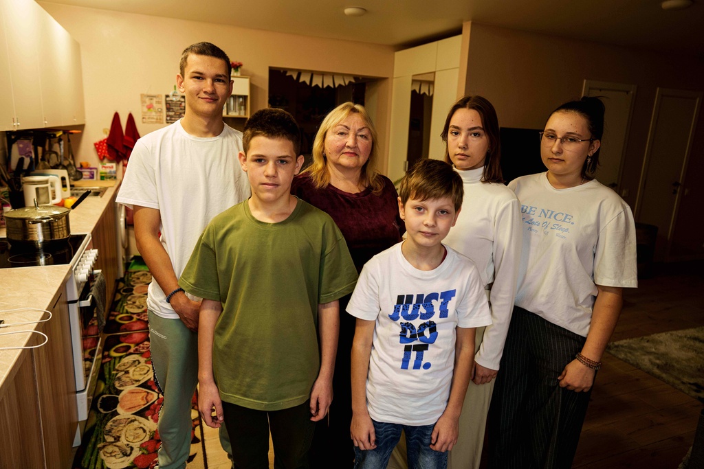 From left, Mykyta Bogomol, 16, Ivan, 12, mother Natalia, Oleksandr 9, Sofia, 17, and Lilia 15, pose at their home in Hansen Village complex in Tarasivka, Ukraine, Thursday, Oct. 2, 2025. (AP Photo/Evgeniy Maloletka)
