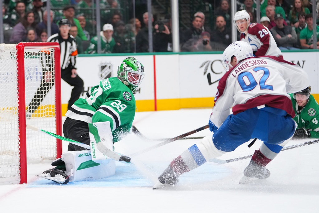 Dallas Stars goaltender Jake Oettinger, left, blocks a shot as Colorado Avalanche left wing Gabriel Landeskog (92) attacks during the second period of an NHL hockey game Friday, March 6, 2026, in Dallas. (AP Photo/Julio Cortez)