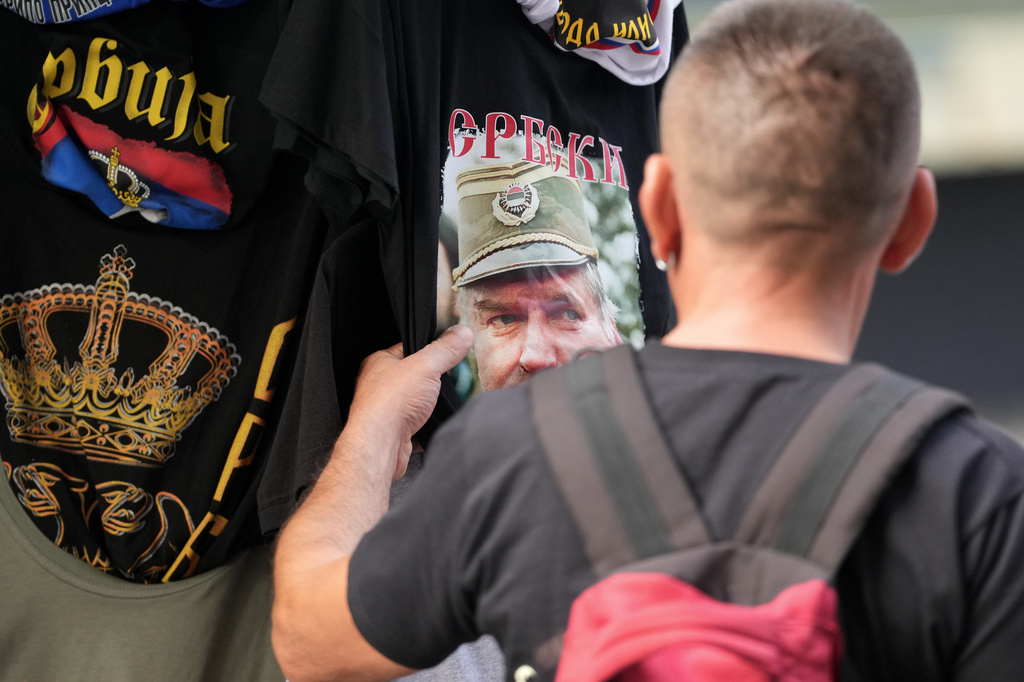 A buyer checks a T-shirt with a picture of former Bosnian Serb wartime general Ratko Mladic displayed on Belgrade's main pedestrian street, Serbia, Friday, Sept. 4, 2026. (AP Photo/Darko Vojinovic)