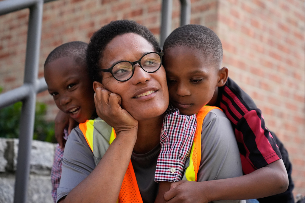 Sechita McNair, center, and sons Derrick McNair-White, right, and Malachi McNair-Nesbitt, left, have breakfast on the steps of Midtown High School on June 11, 2025, in Atlanta. (AP Photo/Brynn Anderson)