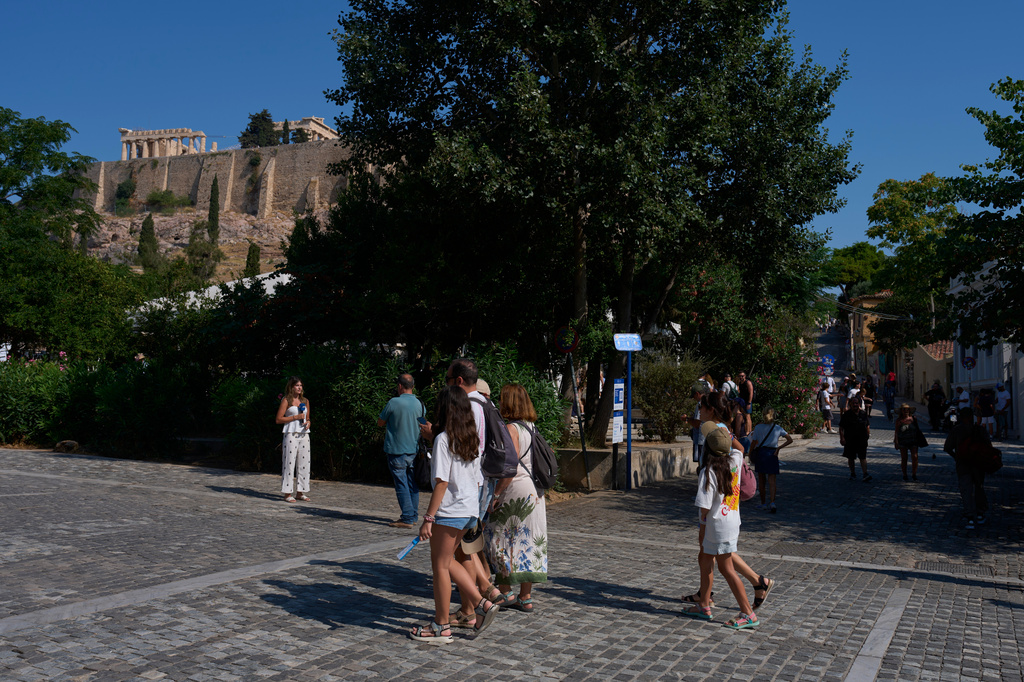 Tourists walk near the Acropolis in Athens, Greece, Tuesday, July 21, 2026, after two tourists were stabbed and injured nearby in an attack on a pedestrian street near the entrance to the archaeological site. (AP Photo/Petros Giannakouris)
