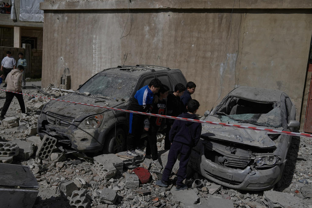 People inspect damaged cars near a building destroyed in an Israeli strike in the village of Temnine in eastern Lebanon, Saturday, Feb. 21, 2026. (AP Photo/Bilal Hussein)
