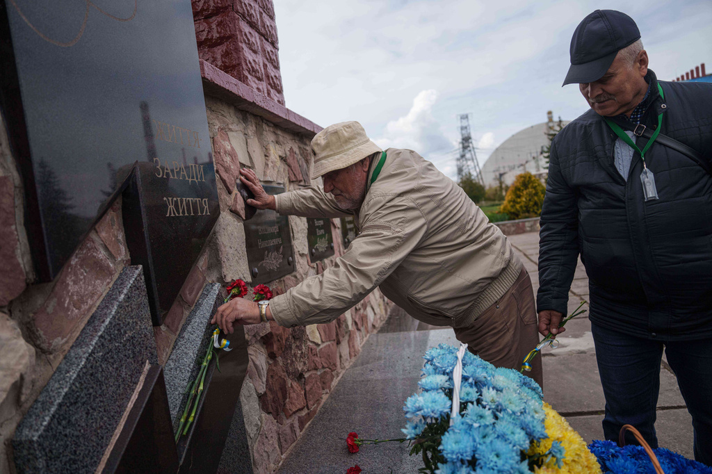 Workers sent to help clean up the effects of the 1986 Chernobyl nuclear power plant accident, place flowers at a monument in front of the facility, Tuesday, April 21, 2026, in Chernobyl, Ukraine. (AP Photo/Evgeniy Maloletka)