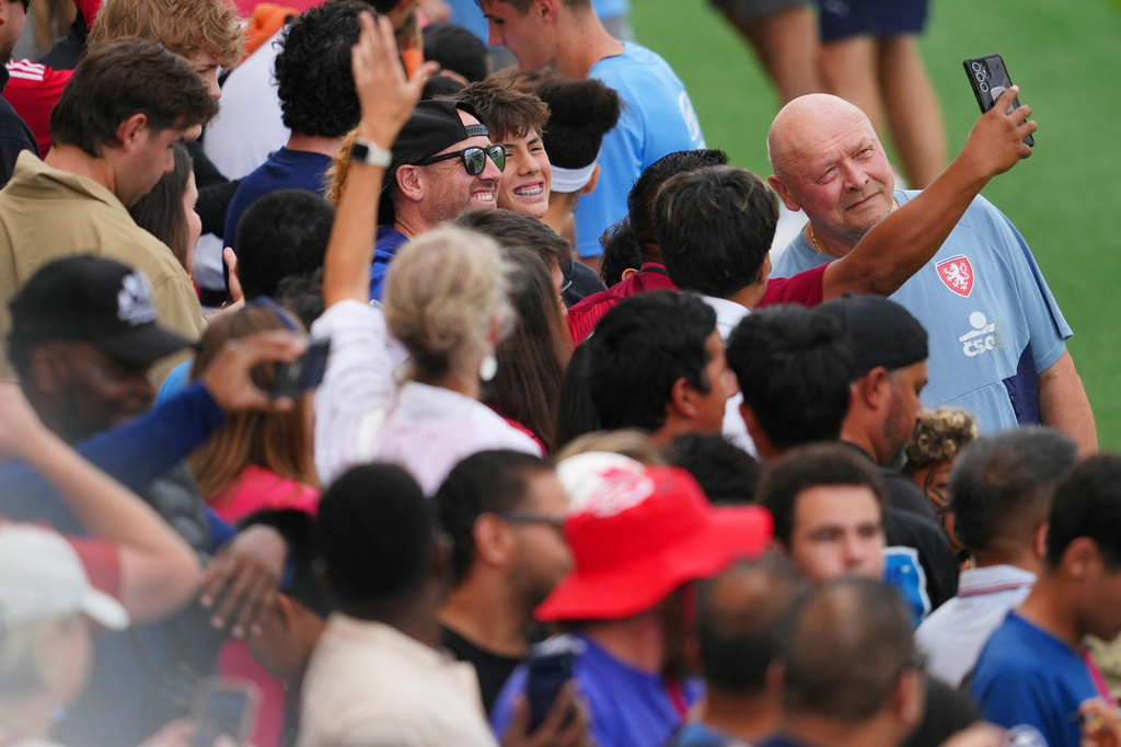 Miroslav Koubek, right, head coach of the Czechia men's national soccer team, poses for a selfie with a supporter during a public training session, Saturday, June 6, 2026, in Mansfield, Texas, ahead of the World Cup soccer tournament. (AP Photo/Julio Cortez)