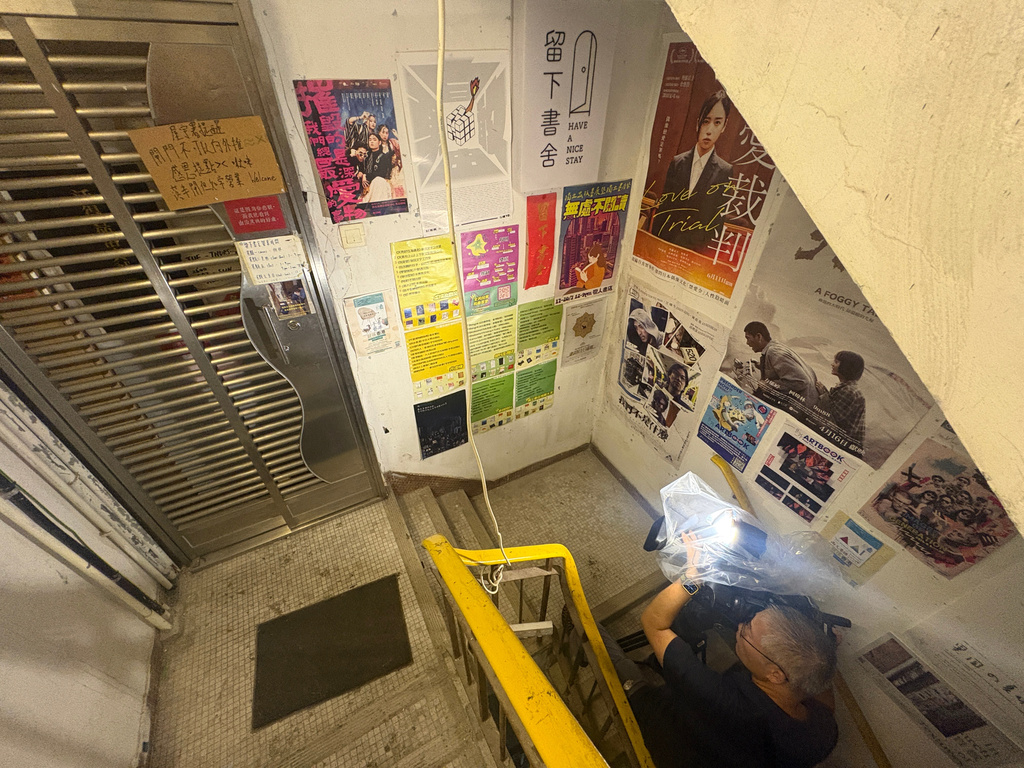 A journalist films the exteriors of the bookstore 'Have A Nice Stay' in Prince Edward district, Hong Kong, Wednesday, July 15, 2026. (AP Photo/Kanis Leung)