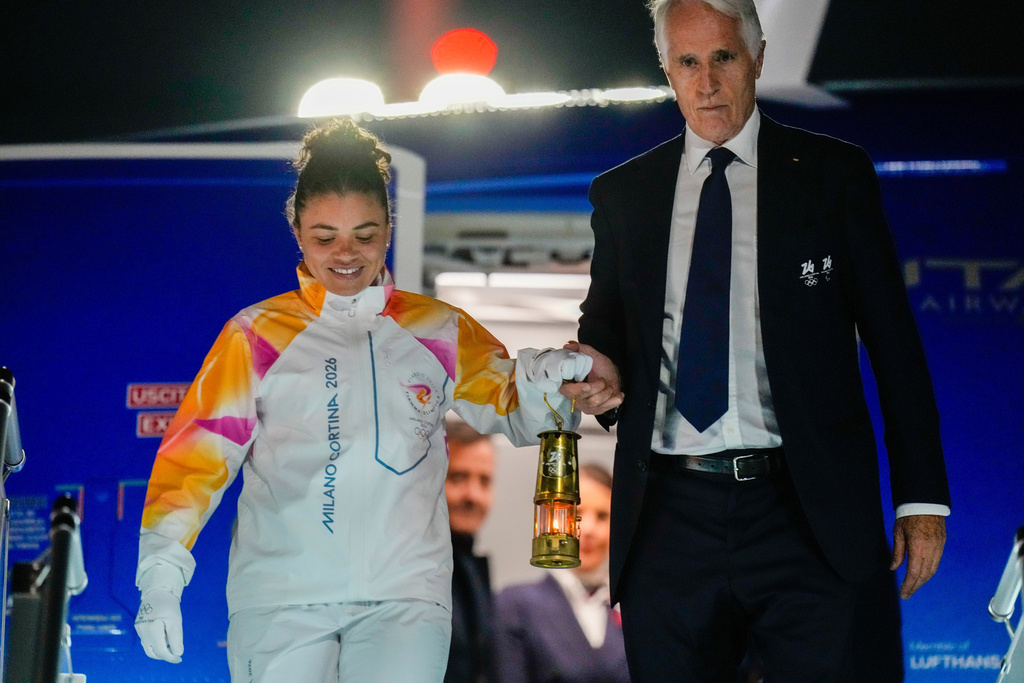 President of the Milano Cortina Organising Committee Giovanni Malago, right, and Italian Olympic medalist tennis player Jasmine Paolini hold a lantern with the Olympic flame as they arrive at Rome's International airport Leonardo da Vinci from Athens, Thursday, Dec. 4, 2025. (AP Photo/Gregorio Borgia)