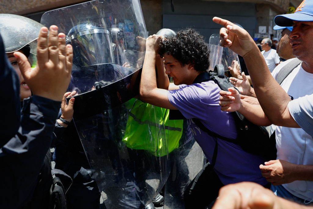 Bolivarian National Police prevent protesters who are demanding higher salaries, pensions and benefits, from continuing their march to the Miraflores Presidential Palace in Caracas, Venezuela, Thursday, April 9, 2026. (AP Photo/Pedro Mattey)