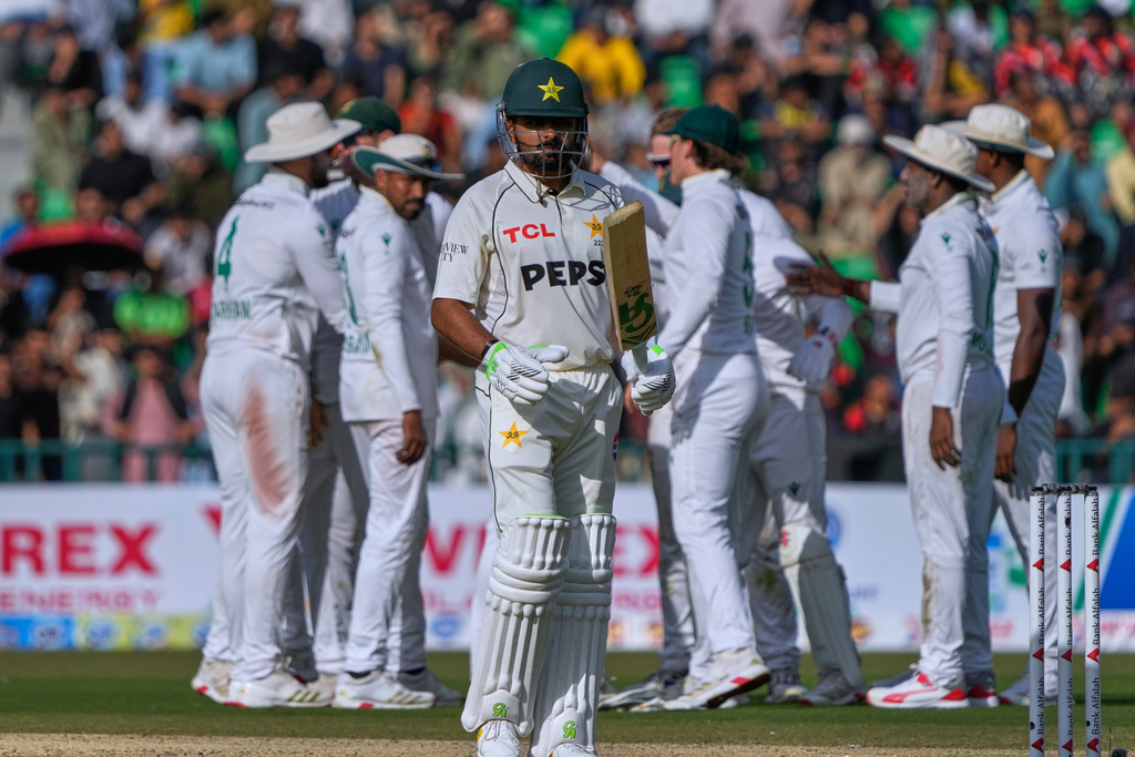 Pakistan's Babar Azam, front, walks off the field as South African players celebrate after his dismissal during the first day of first test cricket match between Pakistan and South Africa, in Lahore, Pakistan, Sunday, Oct. 12, 2025. (AP Photo/K.M. Chaudary)
