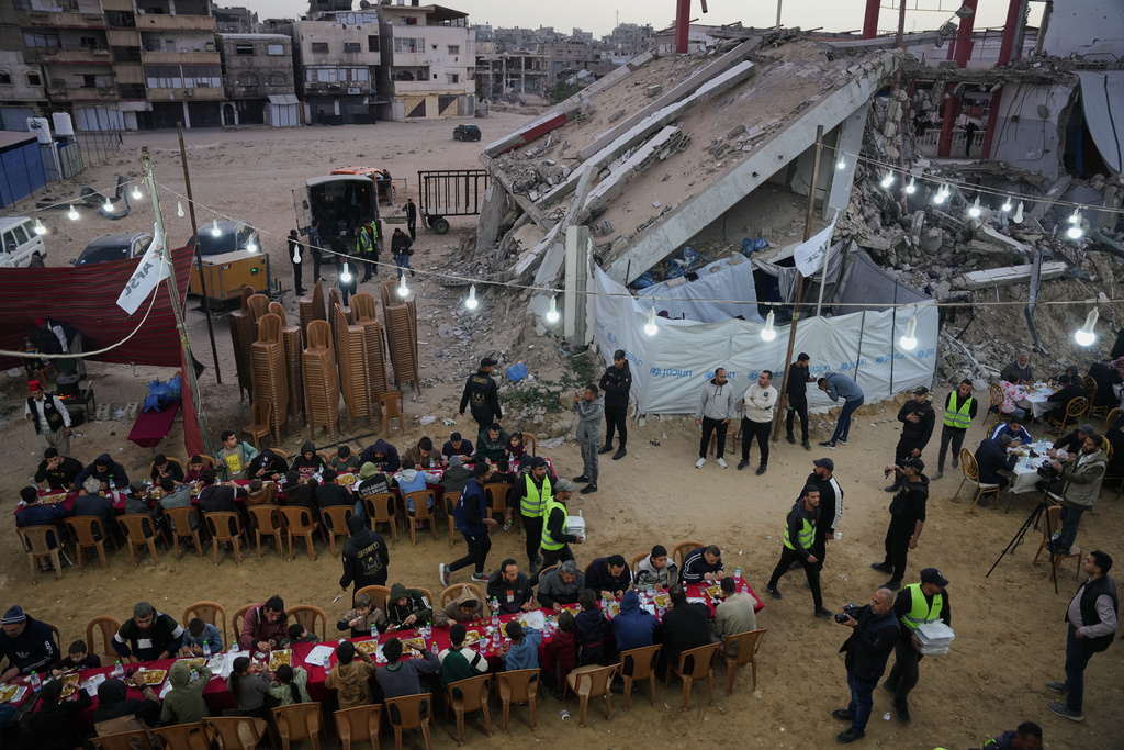 Palestinians sit at a long table amid the rubble of destroyed buildings as they gather for iftar, the fast-breaking meal, on the first day of the Muslim holy month of Ramadan in Khan Younis, Gaza Strip, Wednesday, Feb. 18, 2026. (AP Photo/Abdel Kareem Hana)