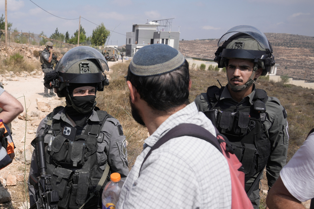 Israeli army soldiers turn back activists who marched with food and water supplies toward the houses of three Palestinian families that have been besieged by Israeli settlers for six days, in the occupied West Bank village of Qusra, south of Nablus, Friday, Aug. 14, 2026. (AP Photo/Majdi Mohammed)