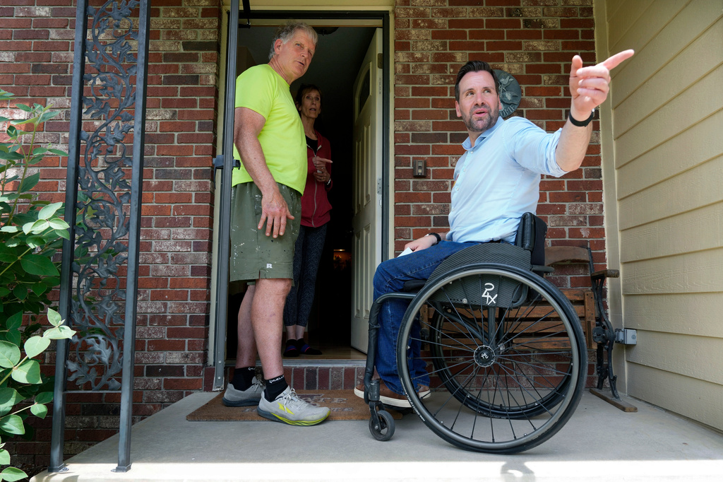 Iowa state Rep. Josh Turek, a Democratic candidate for U.S. Senate, talks with Dave, left, and Lynnae Lathrop while canvassing, Sunday, May 31, 2026, in Waukee, Iowa. (AP Photo/Charlie Neibergall)