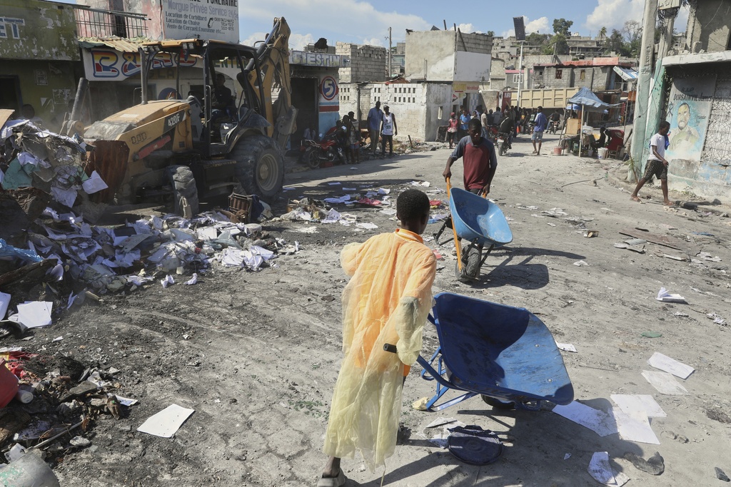 Youths use wheelbarrows to carry debris out of their homes, which were damaged by gang violence, in the Solino neighborhood of Port-au-Prince, Haiti, Wednesday, Sept. 10, 2025. (AP Photo/Odelyn Joseph)