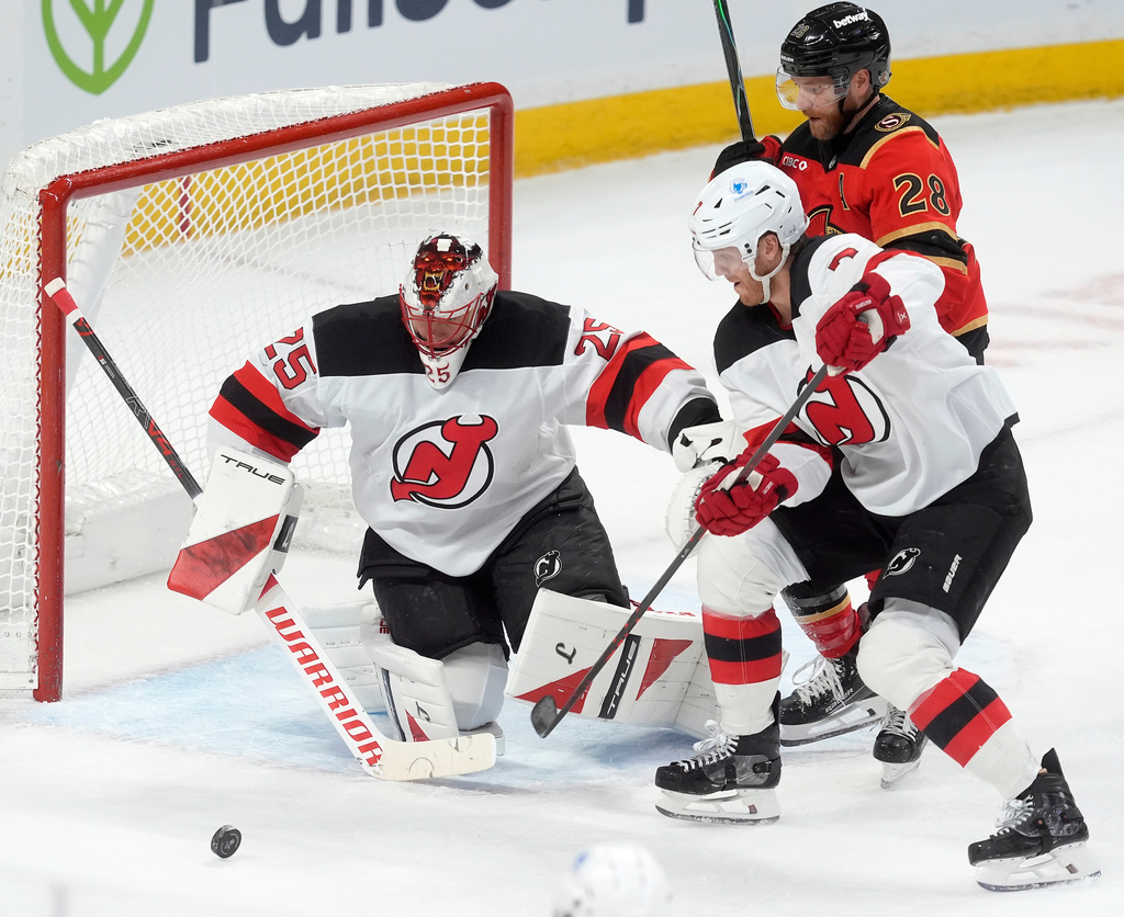 New Jersey Devils goaltender Jacob Markstrom (25) keeps his eye on the puck as teammate Dougie Hamilton (7) clears it away from Ottawa Senators' Claude Giroux (28) during first period NHL action, in Ottawa, Tuesday, Dec. 9, 2025. (Adrian Wyld/The Canadian Press via AP)