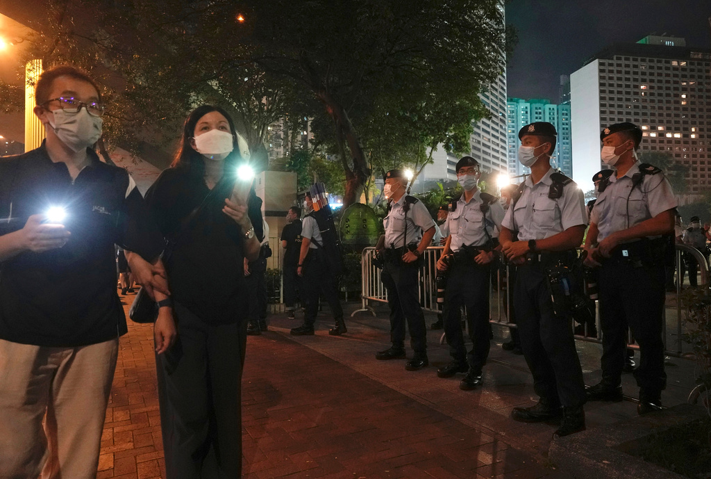FILE - People hold candles walk past police officers near Hong Kong Victoria Park, a place in the past years for people to gather during a candlelight vigil to mark the anniversary of the military crackdown on a pro-democracy student movement in Beijing, in Hong Kong, on June 4, 2021. (AP Photo/Vincent Yu, File)