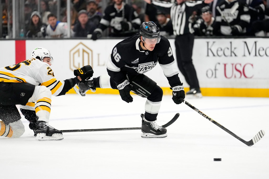 Los Angeles Kings left wing Andrei Kuzmenko, right, moves the puck while under pressure from Boston Bruins defenseman Andrew Peeke during the second period of an NHL hockey game Friday, Nov. 21, 2025, in Los Angeles. (AP Photo/Mark J. Terrill)