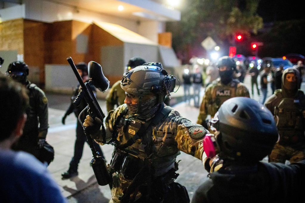Police and Federal officers stand guard an area by the U.S. Immigration and Customs Enforcement facility in Portland, Ore. on Sunday, Oct. 5, 2025. (AP Photo/Ethan Swope)
