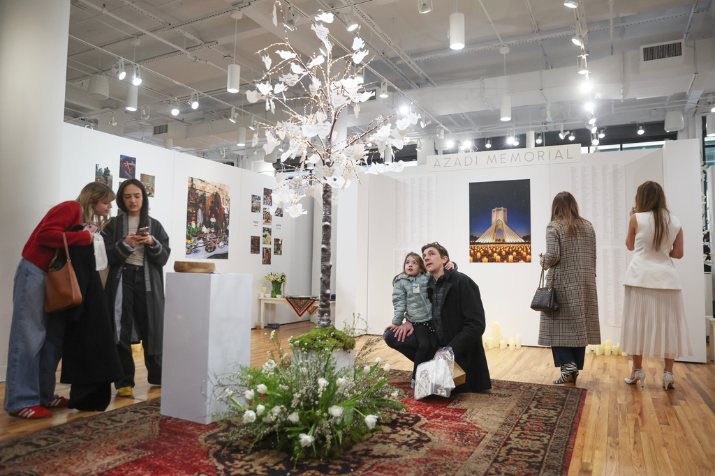 People interact with a dedicated memorial space to Iranian lives that were lost during a gathering in New York, on Saturday, March 14, 2026, for the upcoming Nowruz, Iranian/Persian New Year's day. (AP Photo/Heather Khalifa)