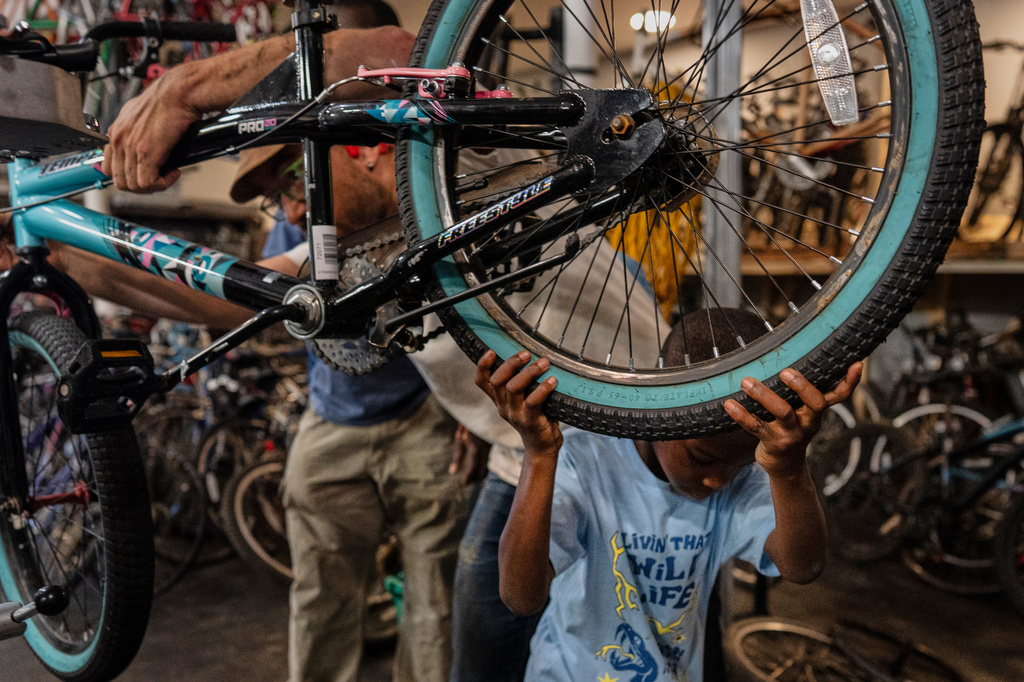 Vincent Wilson, left, who takes in donated, broken bikes and offers them up to the community for anyone who helps fix them up, repairs a bike with the help of a seven-year-old boy at Bikes and Stuff in Lockland, Ohio, Friday, July 10, 2026. (AP Photo/Carolyn Kaster)
