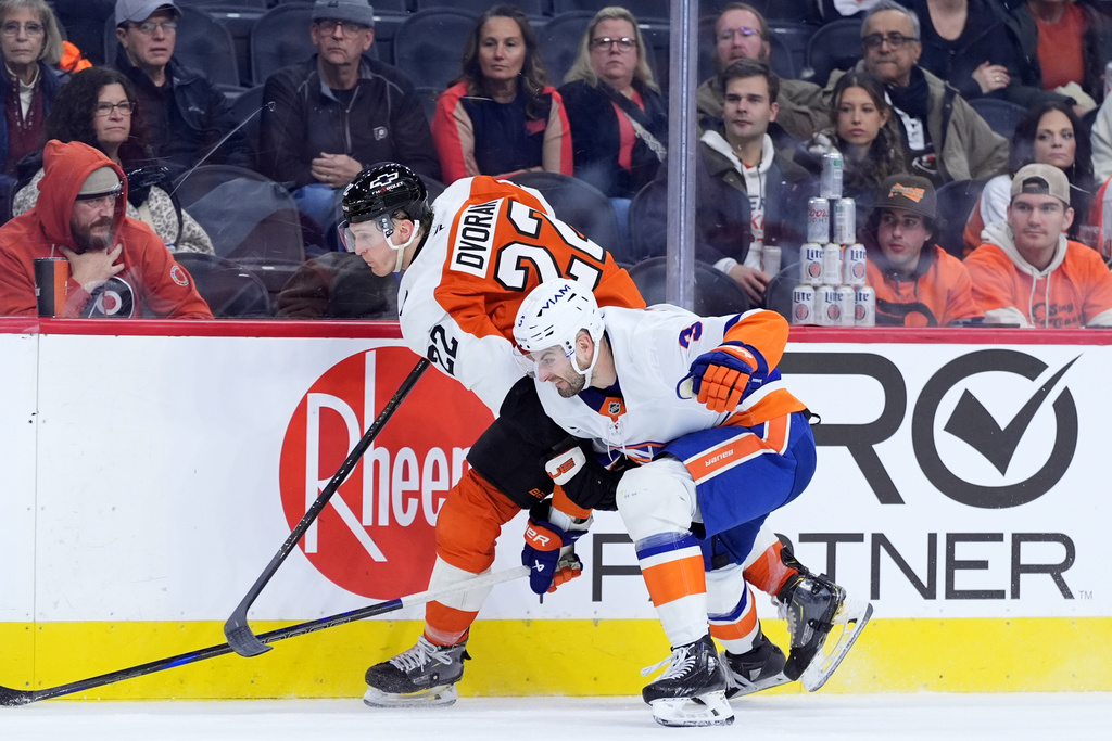 Philadelphia Flyers' Christian Dvorak, left, tries to get past New York Islanders' Adam Pelech during the second period of an NHL hockey game Monday, Jan. 26, 2026, in Philadelphia. (AP Photo/Matt Slocum)