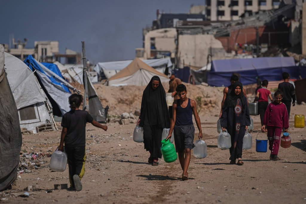 Palestinians carry jerrycans and plastic bottles with water after collecting it at a camp for displaced people in Gaza City, Thursday Oct. 23, 2025. (AP Photo/Abdel Kareem Hana)