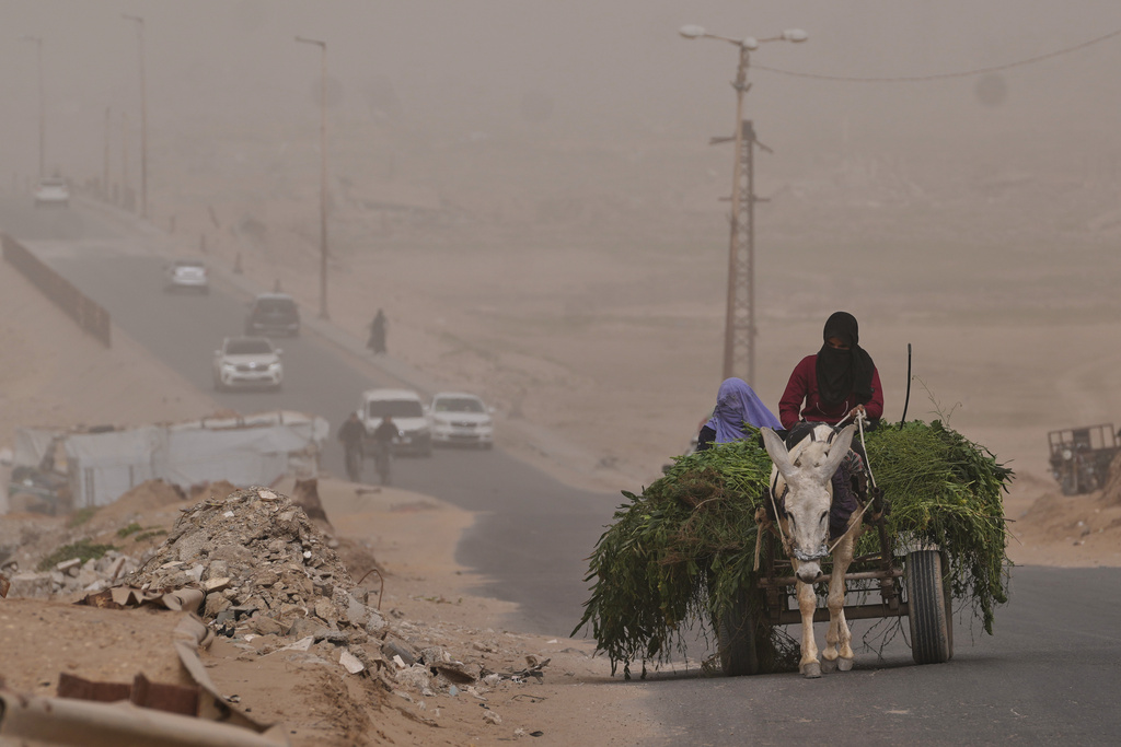 Palestinian women ride a donkey cart along the coastal road in Wadi Gaza during a dust storm in the central Gaza Strip, Saturday, Feb. 14, 2026. (AP Photo/Abdel Kareem Hana)