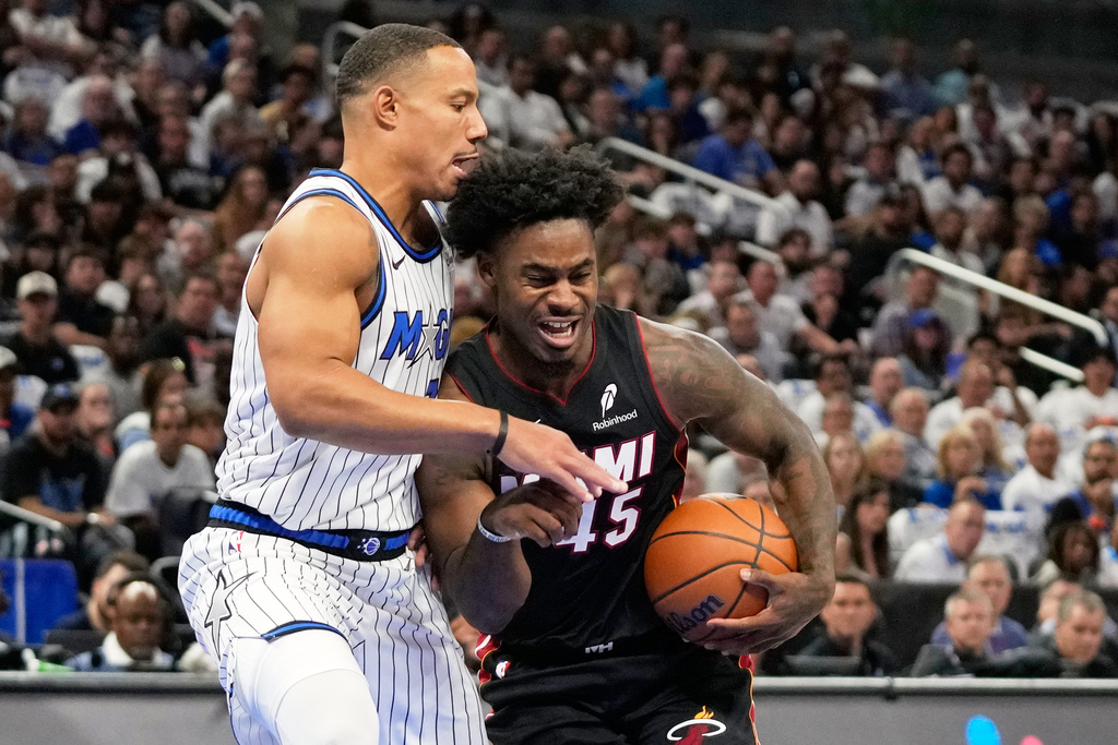 Miami Heat guard Davion Mitchell, right, drives around Orlando Magic guard Desmond Bane during the first half of an NBA basketball game, Wednesday, Oct. 22, 2025, in Orlando, Fla. (AP Photo/John Raoux)