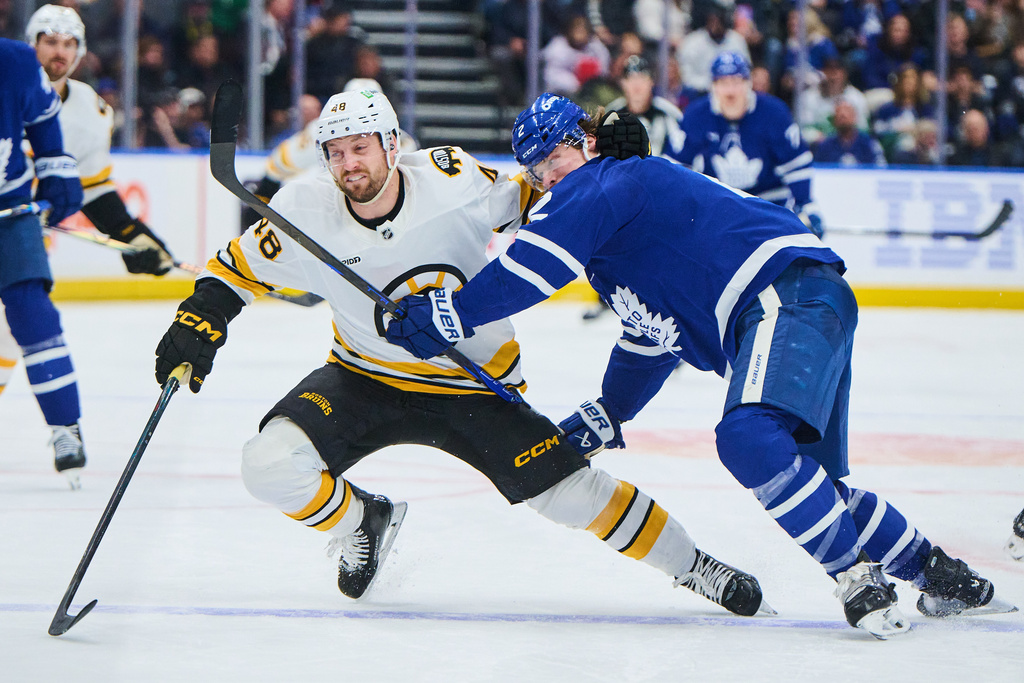 Boston Bruins' Jeffrey Viel (48) and Toronto Maple Leafs' Simon Benoit (2) battle for the puck during third period NHL hockey action in Toronto, on Saturday, Nov. 8, 2025. (Sammy Kogan/The Canadian Press via AP)