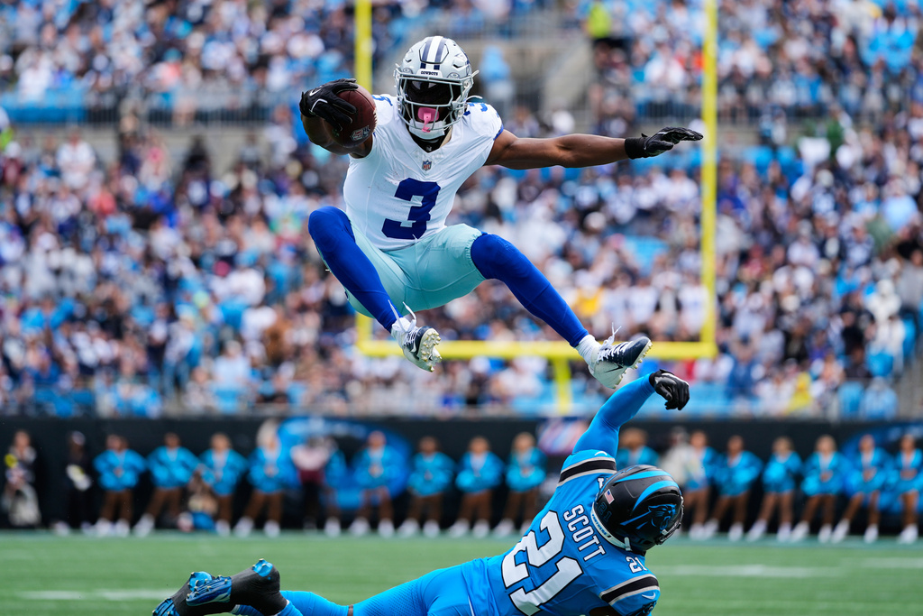 Dallas Cowboys wide receiver George Pickens (3) leaps over Carolina Panthers safety Nick Scott (21) after catching a pass in the first half of an NFL football game, Sunday, Oct. 12, 2025, in Charlotte, N.C. (AP Photo/Erik Verduzco)
