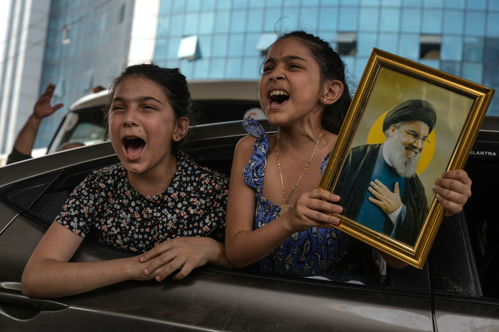Two girls chant slogans as one holds an image of the late Hezbollah leader Hassan Nasrallah in Dahiyeh, Beirut's southern suburbs, Lebanon, Friday, April 17, 2026, following a ceasefire between Israel and Hezbollah. (AP Photo/Bilal Hussein)