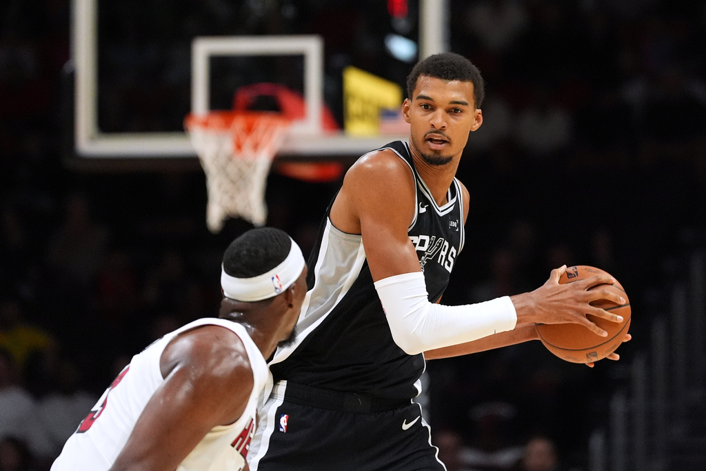 San Antonio Spurs forward/center Victor Wembanyama catches a pass defended by Miami Heat center/forward Bam Adebayo during the first half of a preseason NBA basketball game, Wednesday, Oct. 8, 2025, in Miami. (AP Photo/Rebecca Blackwell)