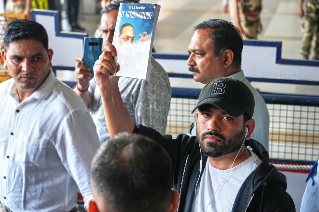 Abhijeet Dipke, center, founder of Cockroach Janta Party shows the autobiography of Bhim Rao Ambedkar as he comes out at Indira Gandhi International airport in New Delhi, India, Saturday, June 6, 2026. (AP Photo/Manish Swarup)