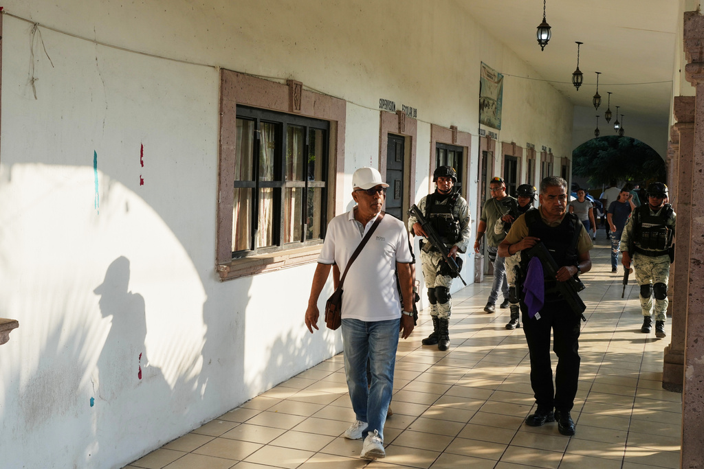 Guadalupe Mora walks with protection from police and the National Guard in La Ruana, Michoacan state, Mexico, Thursday, Nov. 20, 2025. (AP Photo/Eduardo Verdugo)