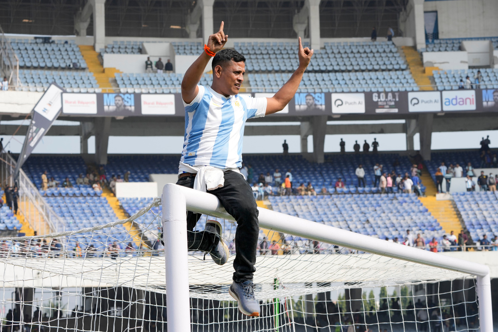 A fan rides a goal post as he protests with others after failing to get a glimpse of Argentine soccer star Lionel Messi at the Salt Lake Stadium, in Kolkata, India, Saturday, Dec. 13, 2025. (AP Photo/Bikas Das)